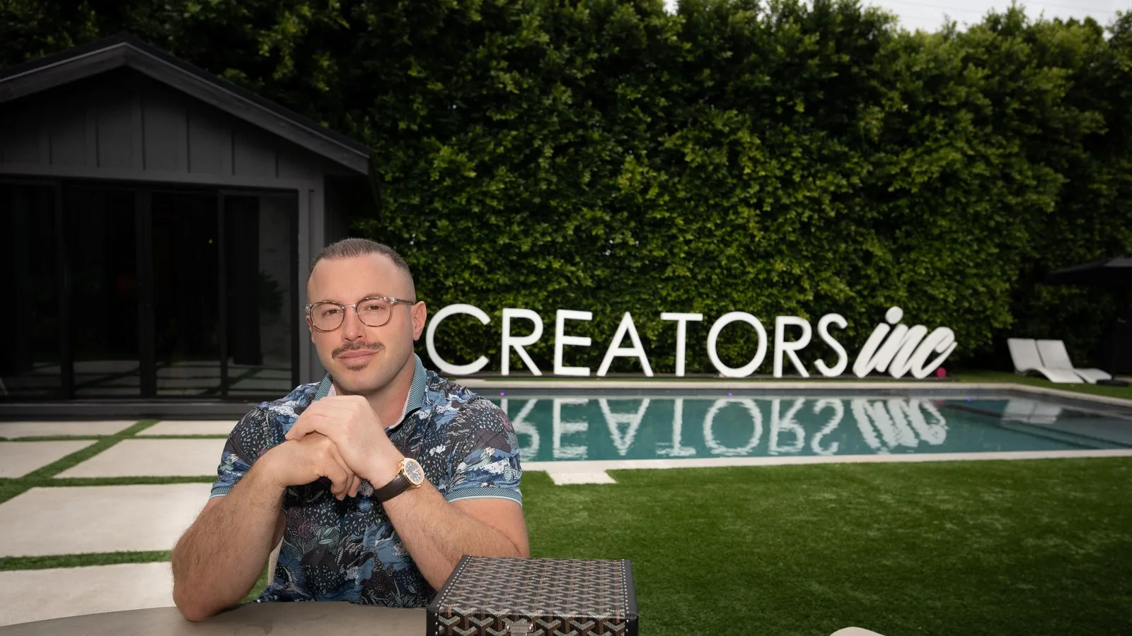 Creators Inc founder Andrew Bachman seated in front of the Creators Inc poolside sign